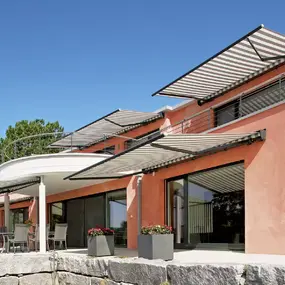 Modernes Einfamilienhaus mit Markisen als Sonnenschutz auf Terrasse und Balkon