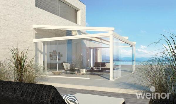 Modernes Glas-Terrassendach an einem Haus mit Meerblick und stilvoller Außeneinrichtung.