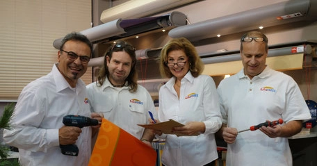 Vier Mitarbeiter im Fachgeschäft präsentieren Werkzeuge und beraten Kunden