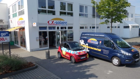 Firmengebäude mit Solar- und Photovoltaik-Branding, Firmenwagen davor
